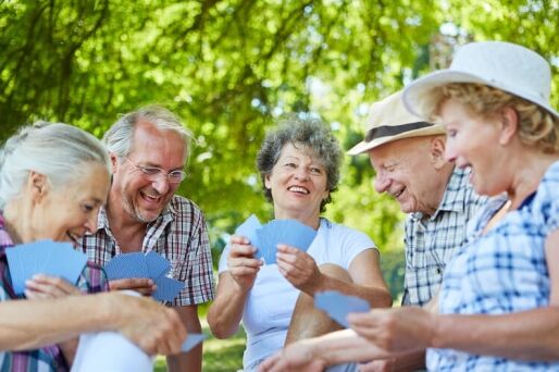 Group of senior friends playing cards outside of their continuing care retirement community.